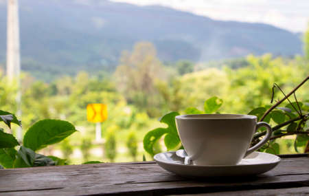 A cup of coffee on a wooden table with natural background.の写真素材