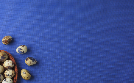 Quail eggs in a basket on blue background. Easter table. Copy space.の写真素材