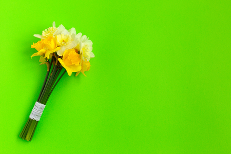 Bunch of yellow narcissus or daffodil flowers on green background. Selective focus. Place for text. Flat lay. Mother's day, easter, birthdayの写真素材