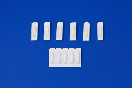 Medical Suppository, Rectal or Vaginal. Isolated on blue Background. Candles for treatment of...