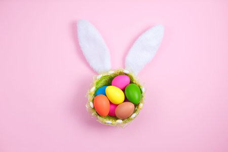 Happy easter with adorable bunny ears on a basket t with colorful eggs against on pink background....