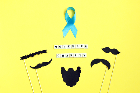 Many black paper Mustache on yellow background. Beard and mustache blue ribbon on yellow background. Concept of prostate cancer. Man health awareness Top view. Copyspace for your text. Novemberの写真素材
