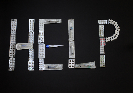 Medical Pills, syringe, thermometer and the word help on a black backgroundの写真素材