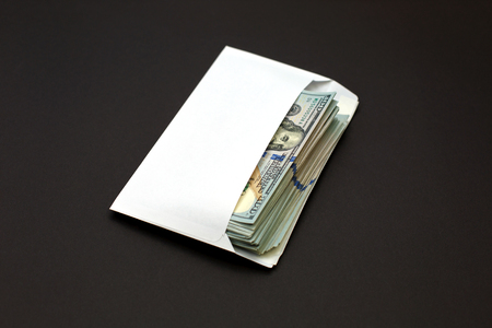 Dollar money in the envelope on black background. bonus, reward, benefits concept, bribe gift. Shadow economy, illegal salary in an envelope without taxesの写真素材