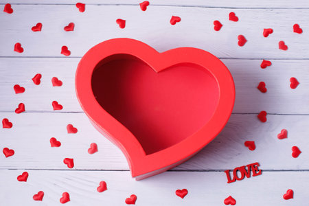 Heart shaped gift box on wood background. Top view of flat lay mockup with romantic decoration...