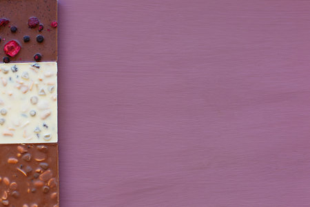 Chocolate on a purple background. Chocolate. Chocolate bar. Nut chocolate. Copy space
