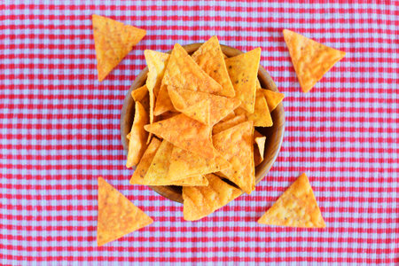 Nachos corn chips on red checkered background. Horizontal