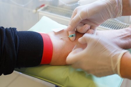 Closeup Hands nurse are using needle to pierce vein Preparation for blood test on table.の写真素材