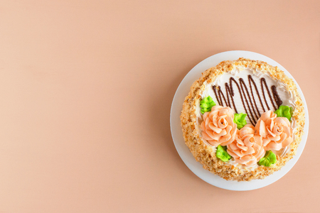 Cream cake of biscuits with creamy roses on the white plate over light background . Top view. Copy space.の写真素材