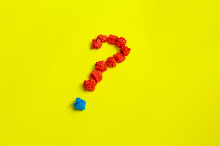 Red question mark lined with crumpled paper balls on yellow background top view copy space. Asking, Decisions. FAQ concept. Concept ideas. Flat lay.の写真素材