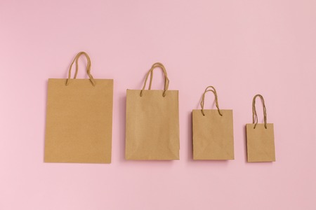 Mock-up of blank craft package, mockup of craft paper shopping bags with handles on pink background. Blank brown paper carrier bags with handles for shopping. Mockup for designの写真素材