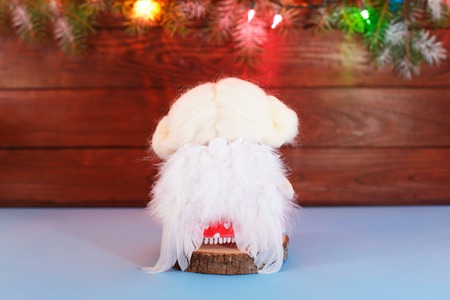 Soft textile handmade angel toy doll sitting back. Cute christmas fairy angel blond in white clothes on wooden background. Merry Christmas backgroundの写真素材