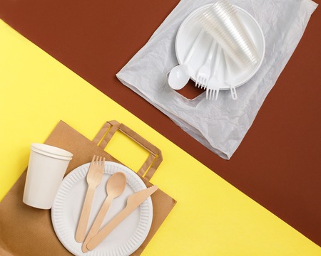 Eco-friendly disposable tableware made of bamboo wood and paper on a yellow background. Plastic harmful dishes and cutlery on brown background. processing and sortingの写真素材
