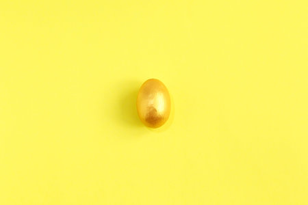 Golden egg, a symbol of making money and successful investment on yellow background. Minimal Happy Easter concept. flatlay.の写真素材