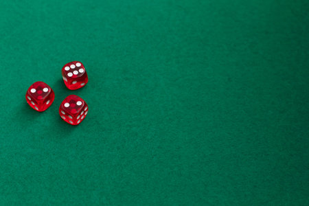Red dice on green and black background. Three red casino dices on green table. Copy space for text