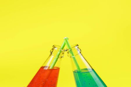 Two bottles of Summer multicolored refreshing drink on yellow background. Exotic healthy beverage. Place for text. Festive concept. party conceptの写真素材