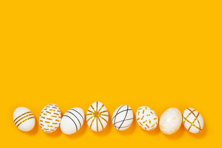 Creative golden Easter eggs on yellow background.