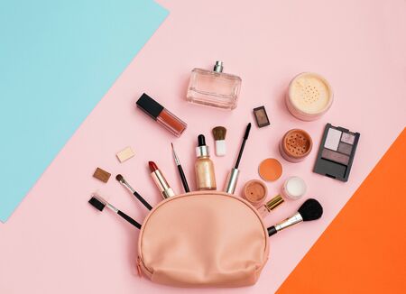 Decorative cosmetic set from pink cosmetic bag on color background. Copy space for your text. Top view, flat lay.の写真素材