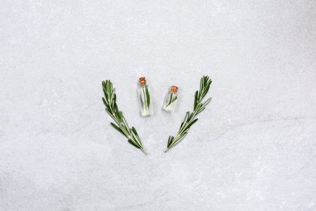 Fresh rosemary and essential oil with fresh rosemary twigs on a light background. Organic cosmetics...