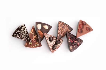 Diferent Piece Handmade chocolate with nuts, dried fruits, seeds on a white background. Chocolate bar. Black and milk chocolate. Chocolate background. Recipe. Copy space.の写真素材