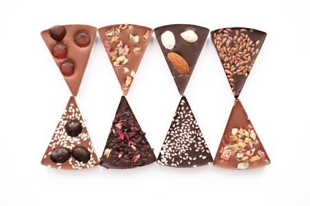 Diferent Piece Handmade chocolate with nuts, dried fruits, seeds on a white background. Chocolate bar. Black and milk chocolate. Chocolate background. Recipe. Copy space.の写真素材