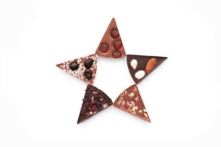 Diferent Piece Handmade chocolate with nuts, dried fruits, seeds on a white background. Chocolate bar. Black and milk chocolate. Chocolate background. Recipe. Copy space.の写真素材