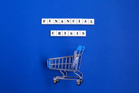 Phrase Financial Crisis and Empty shopping trolley on blue background. Financial crisis concept.の写真素材