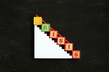 Word CRISIS made from wooden letters lies on white stairsEconomic and financial crisis concept....