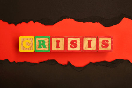 Word CRISIS made from wooden letters lies on a red and black background. Economic and financial...