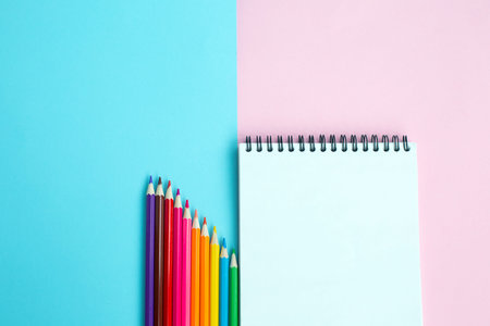 Color pencils and notebook on color background. School and office accessories. school concept. flat...