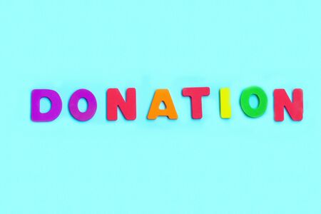 Word DONATION made of colorful letters on blue background. Top viewの写真素材