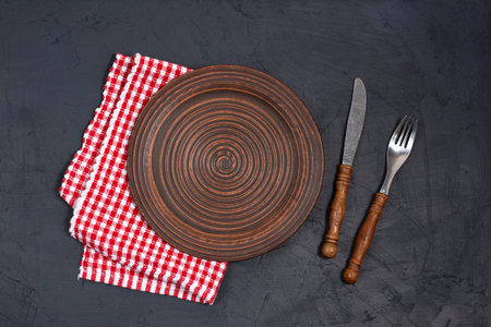 Empty plate and napkin on black background Copy space Top view