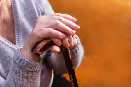 Senior disabled womans hands holding walking stick.