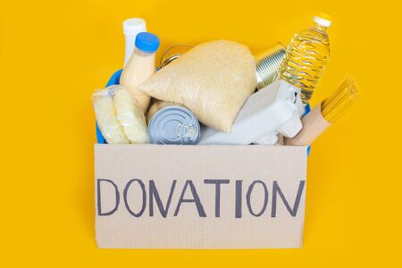 Donation box full of groceries on yellow background. Donation box with various food.の写真素材