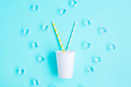 White paper caps with color cocktail straw and ice on blue background. Space for text. recycling eco concept. pop art style. Partyの写真素材