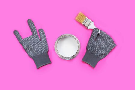 Gray working gloves showing rock sign and white paint with a brush on neon pink backgroundの写真素材