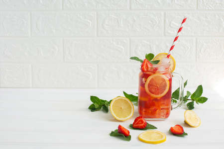 Cold strawberry lemonade juice with ice cubes, lemon and mint on white backgraund. Summer refreshing cocktail.の写真素材
