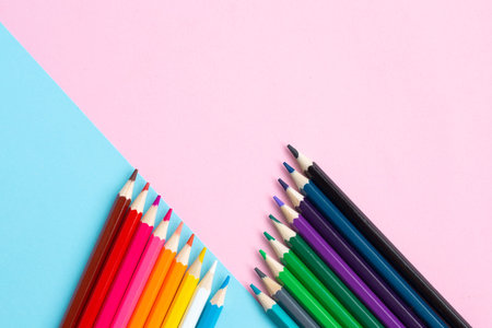 Color pencils on blue and pink background. School and office accessories. school concept. flat lay...
