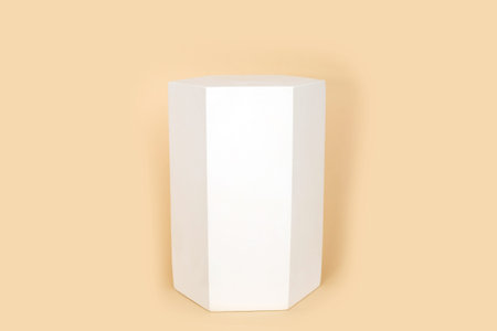 Hexaconal prism geometric figure in white color that casts shape on pastel beige color background. Three-dimensional shape with side in form of hexagon. geometric podium. Fashion magazine.の写真素材
