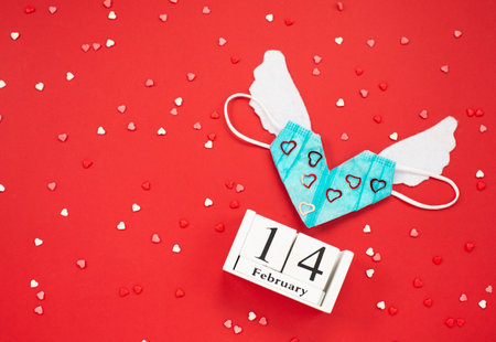 Valentine medical mask with white wings and Wooden calendar show of February 14の写真素材