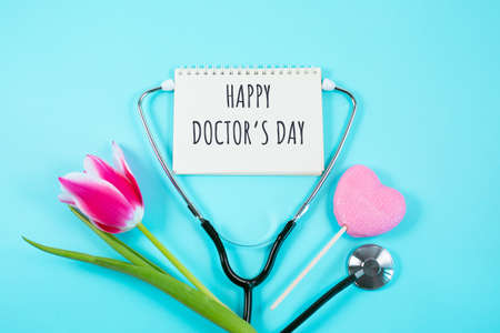 Pink tulip, candy and stethoscope on blue background.の写真素材