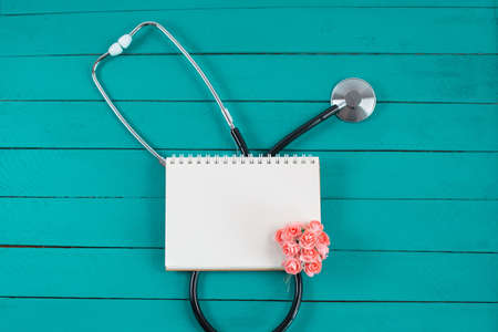Stethoscope with notebook and small pink flowersの写真素材