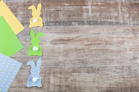 Colorful Easter paper bunnys, rabbits with a tail on wooden table.