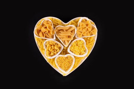 Pasta food selection in heart shaped porcelain dishes over black background.の写真素材