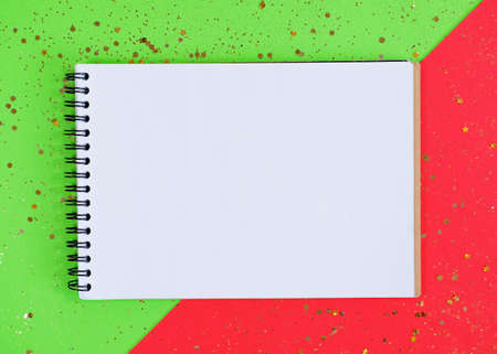 Empty notebook mockup with glittering stars confetti on a red and green background.の写真素材
