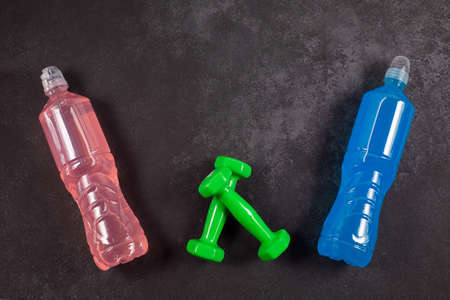 ENERGY DRINK. Bottles with different flavors and dumbbells on a dark background.の写真素材