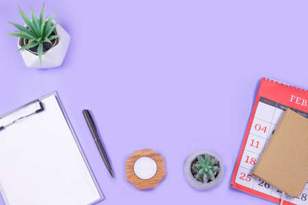 Calendar, Open notebook, pen, with alarm and green flowerpot on purple background.の写真素材