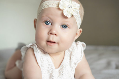 Portrait of a beautiful little baby girl lying on her stomach and looks away with admiration.