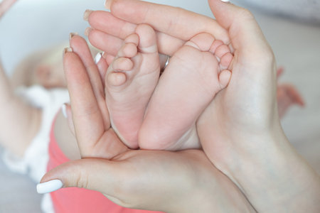 Mother holds Baby feet. Tiny feet in womans hand.