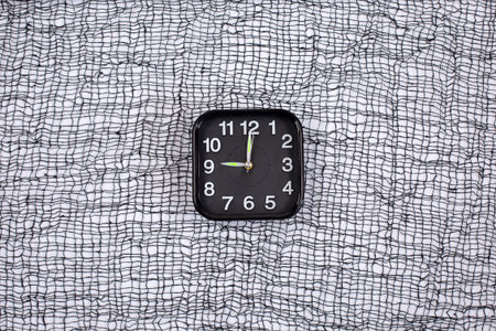 Clock, alarm on a black and white grid background. Time trick.